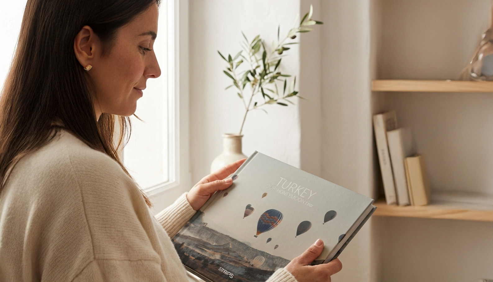 Femme en pull crème regardant son TripBook près d'une fenêtre à la lumière naturelle